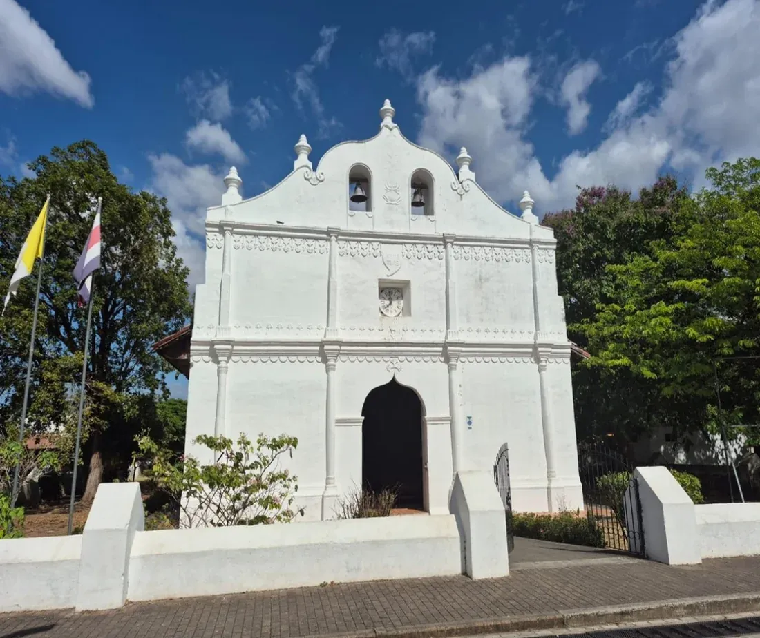 Fachada blanca de la iglesia colonial de San Blas, en el centro de Nicoya, bajo un cielo azul.